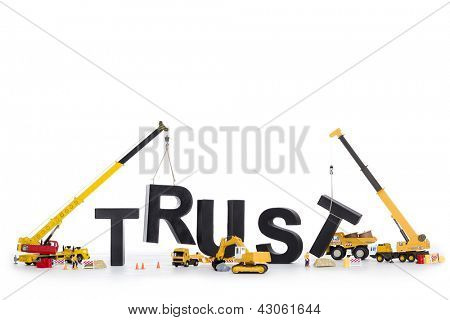 Picture or Photo of Building up trust concept: Black alphabetic letters forming the word trust being set up by group of construction machines, isolated on white background.