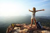 picture of look  - Young woman with backpack standing on cliff - JPG 