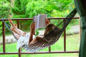 picture of reading  - Young woman reading a book lying in hammock - JPG 