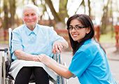 picture of outdoor  - Kind doctor nurse outdoors taking care of an ill elderly woman in wheelchair - JPG 