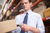 foto of scan  - Businessman Scanning Package In Warehouse - JPG 