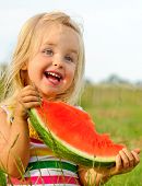 picture of outdoor  - Adorable blonde girl eats a slice of watermelon outdoors - JPG 
