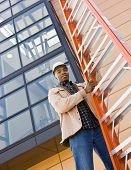 picture of construction worker  - Low angle view of African construction worker lifting ladder - JPG 
