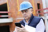 picture of construction  - Entrepreneur on construction site using smartphone - JPG 