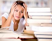 stock photo of final  - Tired female student at the library looking very frustrated - JPG 