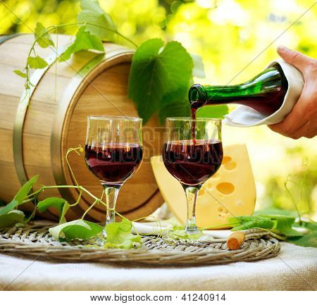Picture or Photo of Wine. Red Wine and Cheese. Romantic Lunch Outdoor. Pouring Wine close-up. Outdoors