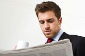 picture of newspaper  - Businessman reading a newspaper while drinking coffee - JPG 