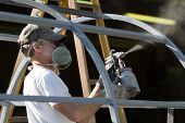 pic of workforce  - Construction worker spray paints while wearing respiratory safety equipment to protect himself from the fumes at a factory - JPG 