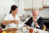 picture of health  - a geriatric nurse helps elderly woman at breakfast - JPG 