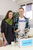 stock photo of community  - couple of young volunteers doing community service with donation box - JPG 