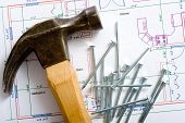 stock photo of construction  - A hammer and nails lying on top of a house floor plan or blue print - JPG 