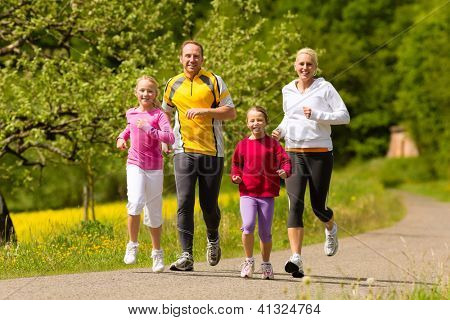 Picture or Photo of Happy Family with two girls running or jogging for sport and better fitness in a meadow in summer