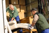 image of transportation  - Two male movers putting furniture and boxes  in moving truck - JPG 