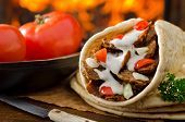 stock photo of food  - A spicy gyro donair with tomatoes and parsley against a hardwood fire background - JPG 