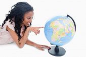 picture of globe  - A young smiling girl is pointing at a globe against a white background - JPG 