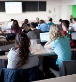 foto of student  - young pretty female college student sitting in a classroom full of students during class - JPG 