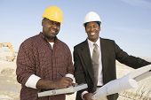 stock photo of construction  - Engineer showing blueprint for a worker at construction site - JPG 