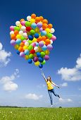 pic of woman  - Happy young woman holding colorful balloons and flying over a green meadow - JPG 