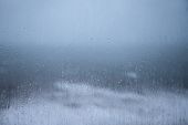 stock photo of stay  - Raindrops on a windowpane smeary blurry and wet the stormy sea and cloudy sky in background with themes of staying indoors on a wet day  - JPG 