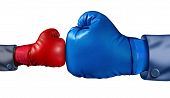 stock photo of competition  - Competition and adversity and fighting the establishment as a new small business against a huge established corporation as a smaller boxing glove versus a huge one as a symbol of overcoming challenges with courage and conviction - JPG 