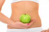stock photo of fitness  - A picture of a woman holding a green apple in front of her fit belly - JPG 