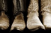 stock photo of contrast  - Two pairs of well worn cowboy boots in high contrast light - JPG 