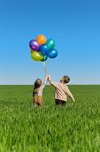 image of brothers  - Happy sister and brother with balloons walking on the spring field - JPG 