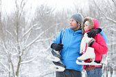 picture of winter  - Young interracial couple in winter carrying ice skates standing close together looking out over a snowy winter landscape with copyspace - JPG 
