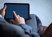 picture of digits  - Businessman with finger touching screen of a digital tablet whilst sitting on a sofa - JPG 