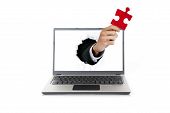 picture of puzzle  - Businessman hand breaking through a screen of laptop holding a piece of puzzle - JPG 