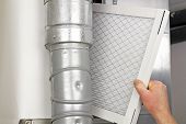 pic of home  - Male arm and hand replacing disposable air filter in residential air furnace - JPG 