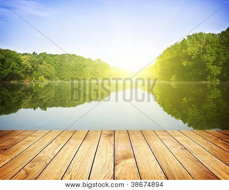 Picture or Photo of Sunset on forest lake and wooden board background