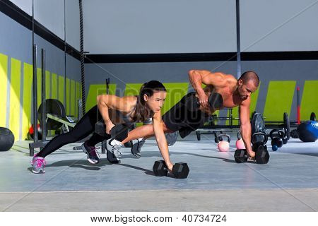 Picture or Photo of Gym man and woman push-up strength pushup with dumbbell in a workout