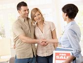 stock photo of agent  - Estate agent congratulating young couple on making deal on new house - JPG 
