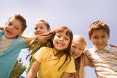 stock photo of children  - Portrait of happy children embracing each other and laughing with pretty girl in front - JPG 