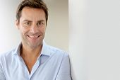 stock photo of interior  - Portrait of handsome and happy guy leaning on wall - JPG 