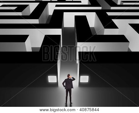 Picture or Photo of Business man in front of a huge maze thinking how to get through