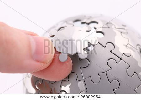 Picture or Photo of Business concept with a hand building puzzle globe on white, space for messages