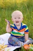 pic of curiosity  - Little baby boy with Down syndrome painting finger paints on white paper with a smile - JPG 