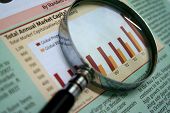 image of venture  - a magnifying glass focusing on a graph in the business section of the newspaper - JPG 