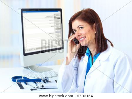 Picture or Photo of Smiling medical doctor woman with computer and telephone.
