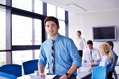 image of meeting  - Portrait of a handsome young  business man  on a meeting in offce with colleagues in background - JPG 