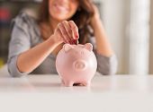 foto of currency  - Woman Putting Coin In Piggy Bank - JPG 