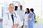 picture of health  - Mature doctor pointing seriously at something on his clipboard - JPG 